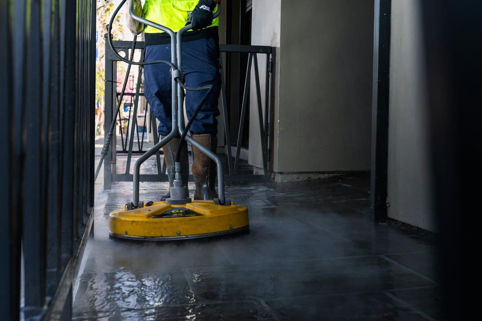Floor care technician restoring a commercial hard floor with a rotary surface scrubber