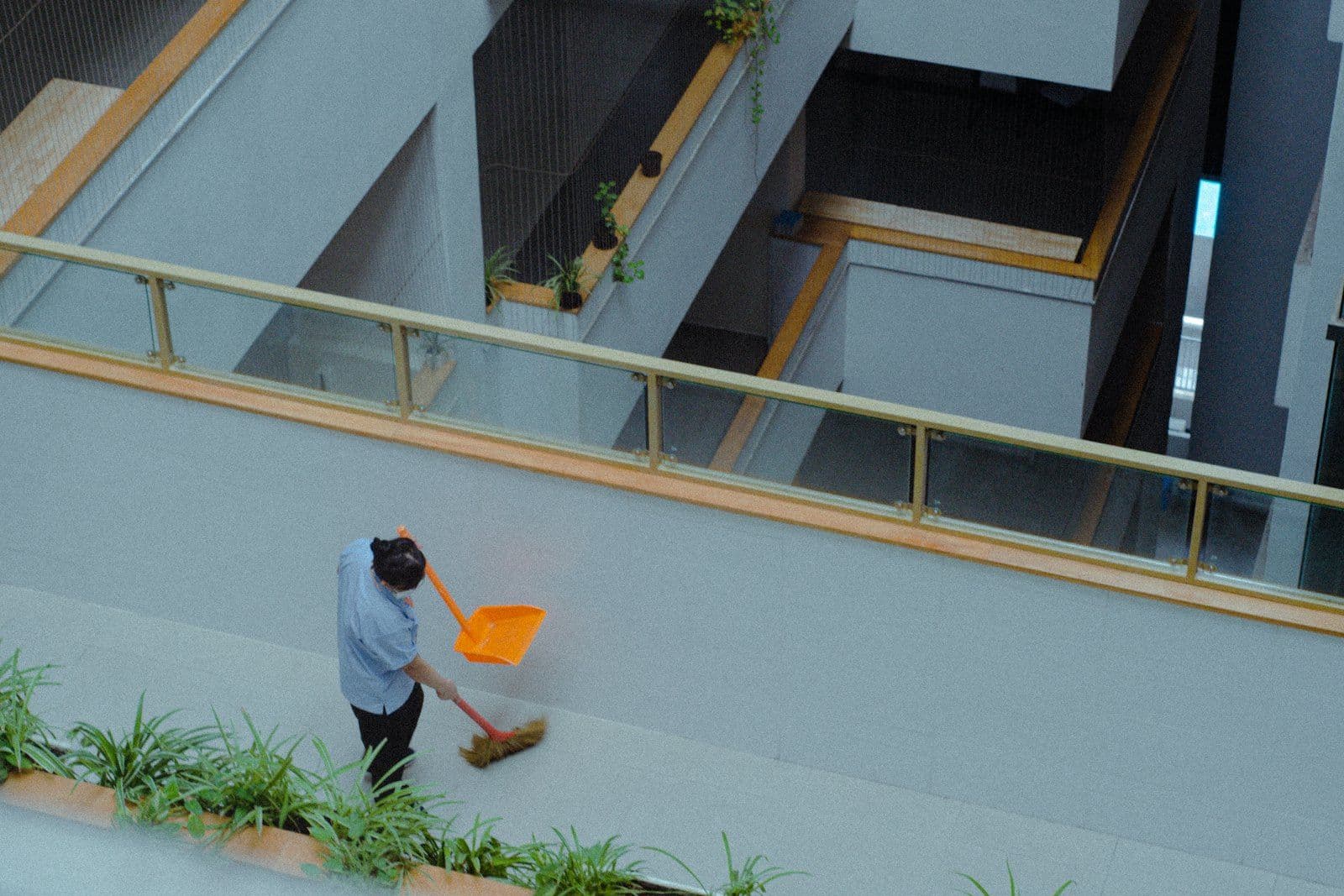 Capital Commercial Services porter sweeping a landscaped walkway outside a commercial building
